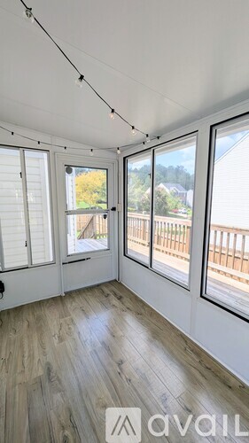 A room with a view of a fence and trees through the windows.