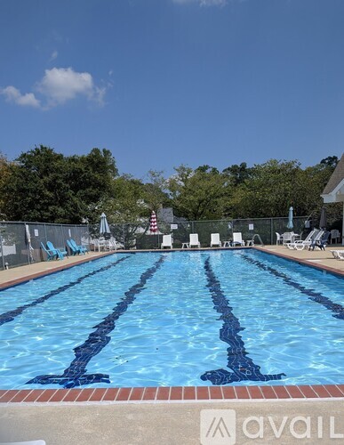 A large outdoor swimming pool with blue water and lounge chairs.