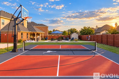 A tennis court is located in a backyard with a slide and a pool.