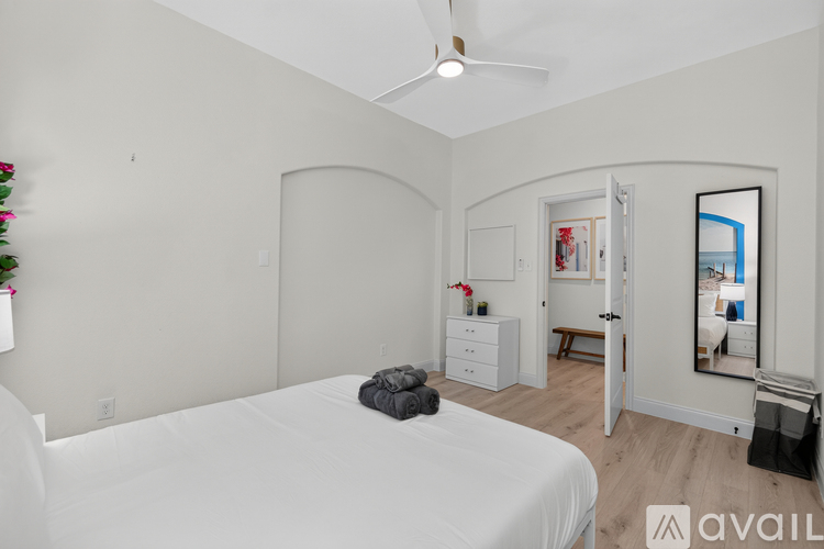 A bedroom with a white bed and a ceiling fan.