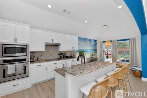A kitchen with white cabinets and a granite countertop.