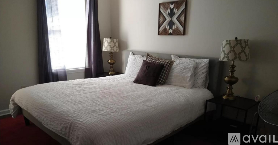 A bedroom with a large bed and two lamps.
