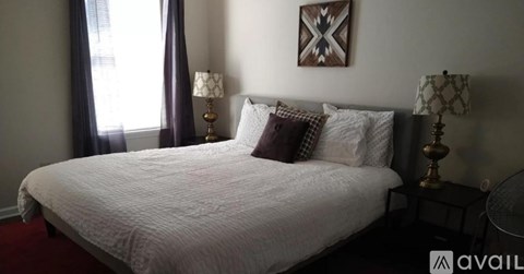 A bedroom with a large bed and two lamps.