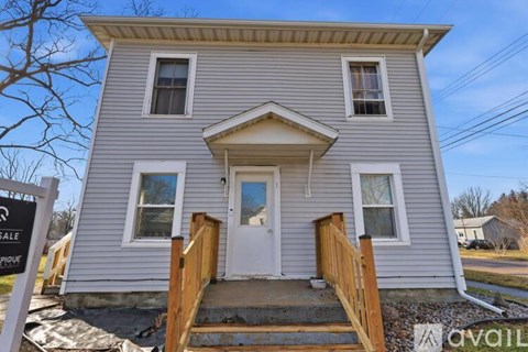 A house with a grey siding and a white door is for sale.