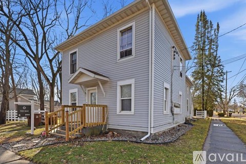 A house with a grey siding and a wooden deck is for sale.