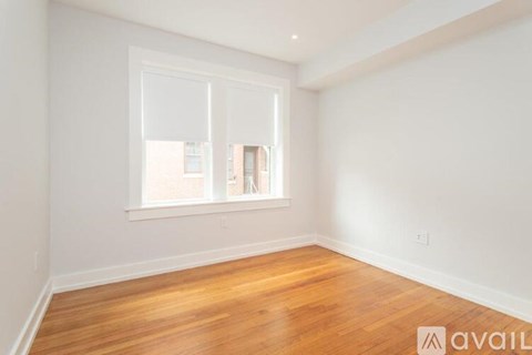 A room with wooden floors and a window showing a view of a building outside.