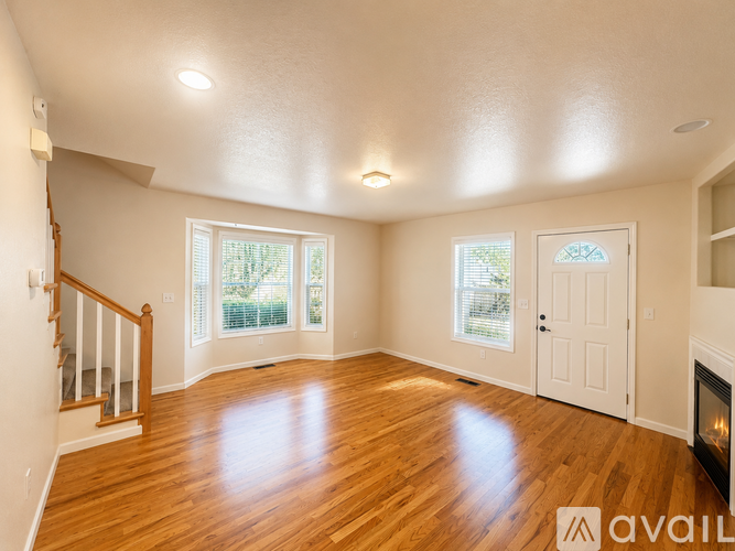 A spacious room with wooden floors and a fireplace.