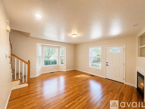 A spacious room with wooden floors and a fireplace.