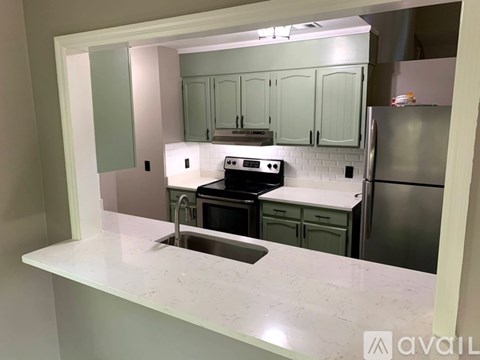 A kitchen with a white countertop and green cabinets.