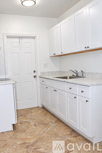 A kitchen with white cabinets and a marble countertop.
