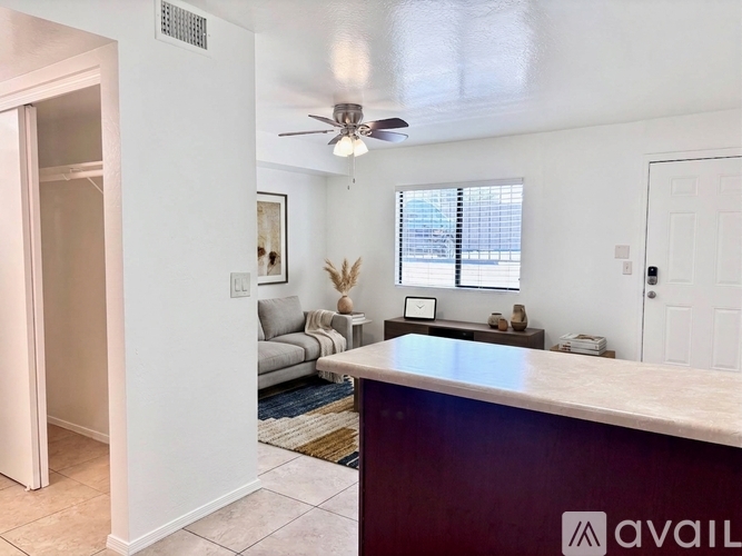 A living room with a couch, a table, and a fan.