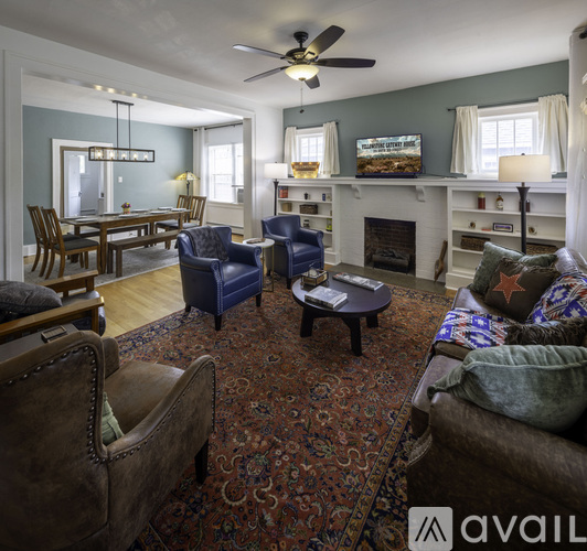 A living room with a fireplace, a couch, a chair, and a rug.