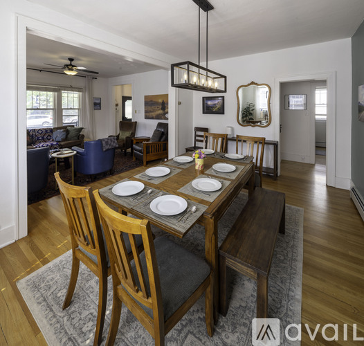 A dining room with a table set for two and chairs around it.