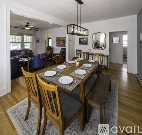 A dining room with a table set for two and chairs around it.