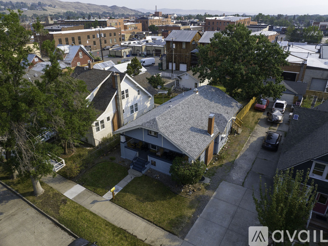 A house with a grey roof is surrounded by other buildings.