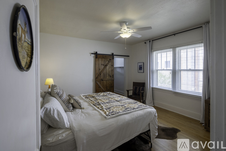 A bedroom with a bed, a ceiling fan, and a window with blinds.