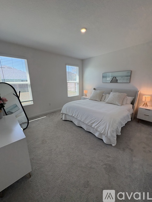 A bedroom with a large bed and a window with blinds.