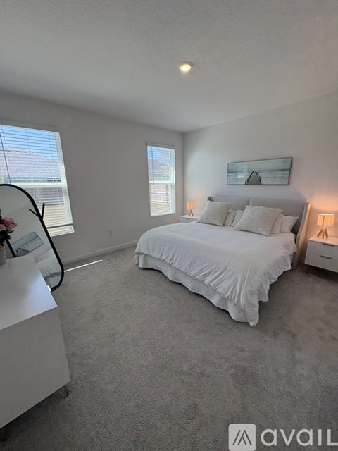 A bedroom with a large bed and a window with blinds.