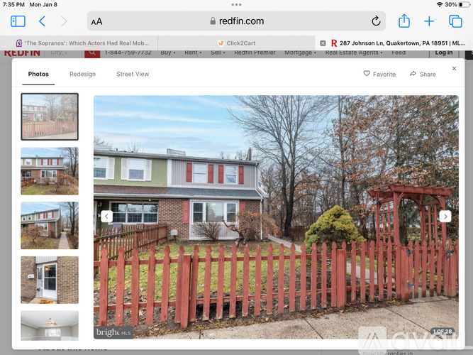 A red fence surrounds a house with a small garden.