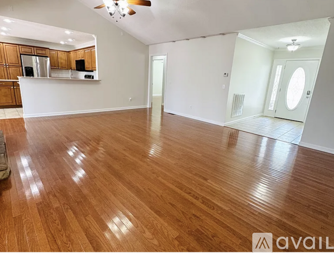 A spacious room with wooden flooring and a bar area.