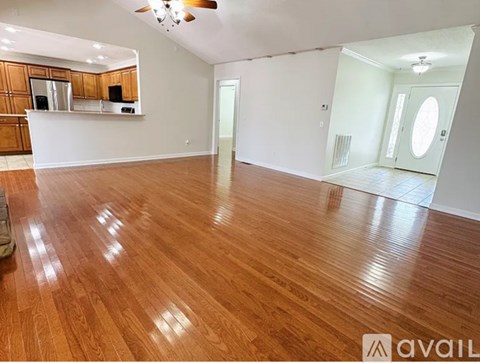 A spacious room with wooden flooring and a bar area.
