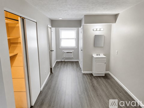 A long hallway with a white cabinet and a window.