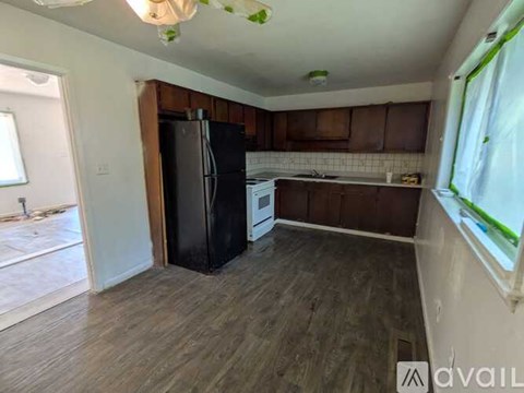 A kitchen with a black refrigerator and wooden flooring.