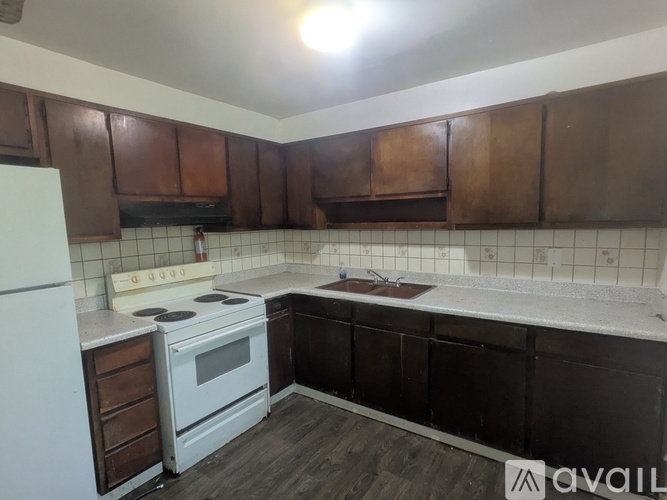 A kitchen with white appliances and brown cabinets.