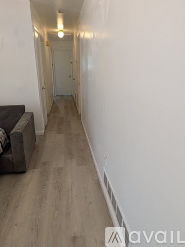 A long hallway with a couch on the left and a door at the end.