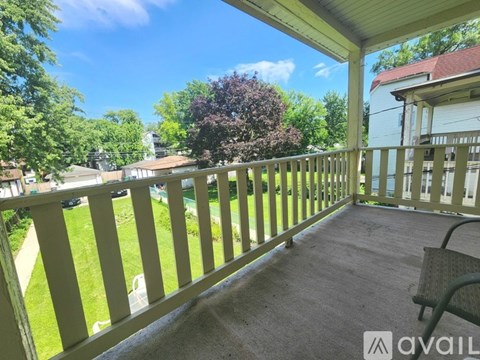 A sunny day on a covered deck with a view of a green lawn and trees.