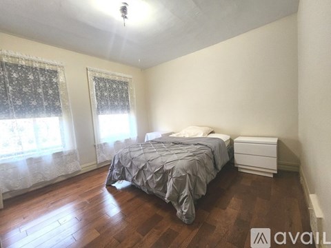 A bedroom with a bed, nightstand, and window with curtains.