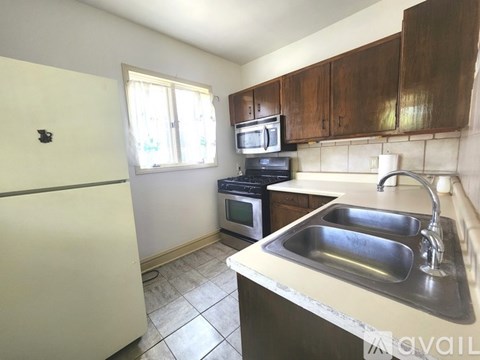 A kitchen with a white fridge, a white sink, and brown cabinets.
