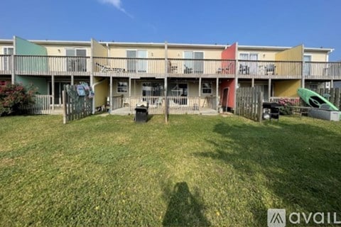 A grassy area in front of a row of apartment buildings.