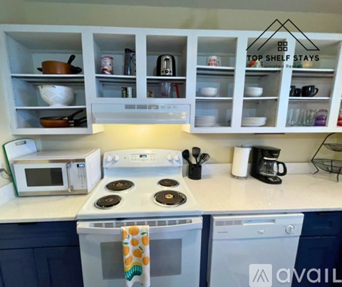 A kitchen with a white stove top and a white microwave oven.