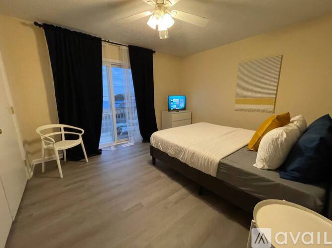 A bedroom with a bed, chair, and a window with curtains.