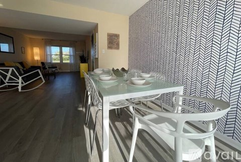 A dining room with a white table and chairs.