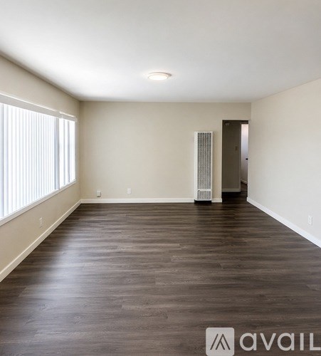 A spacious room with wooden flooring and a door on the right side.