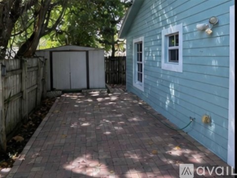 A blue house with a brick walkway in front.
