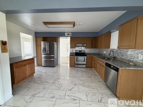 A kitchen with a marble floor and wooden cabinets.