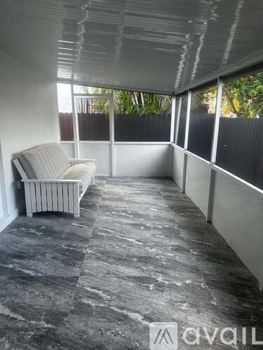 A grey couch sits in a room with grey tiled flooring and white walls.