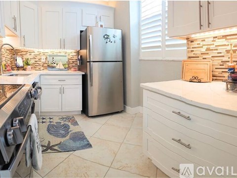 A kitchen with a stainless steel refrigerator and white cabinets.
