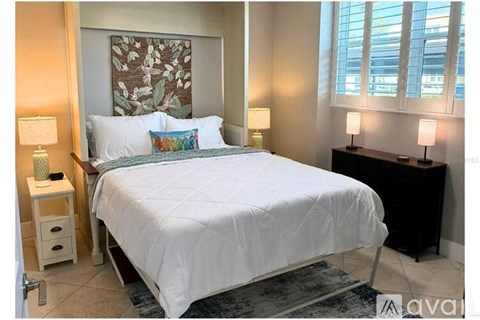 A bedroom with a white bed and a painting on the wall.
