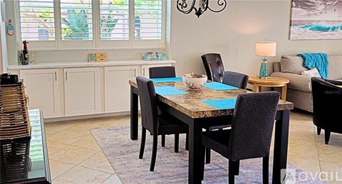 A dining room with a table surrounded by chairs.