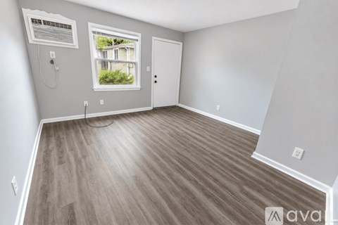 A room with wooden flooring and a window showing a building outside.