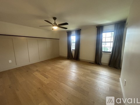 A spacious room with wooden flooring and a ceiling fan.