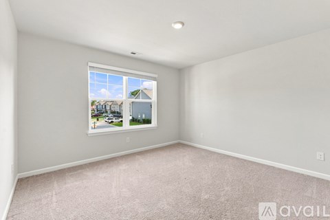 A room with a window showing a view of houses and trees outside.