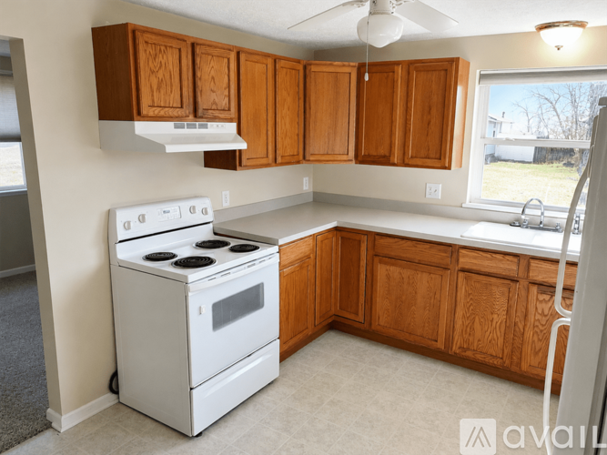 A kitchen with a white stove and wooden cabinets.