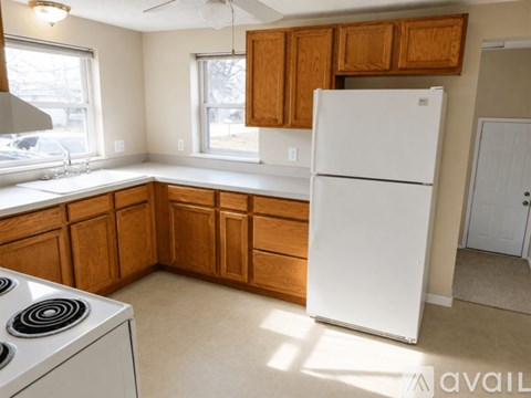 A kitchen with a white fridge and wooden cabinets.