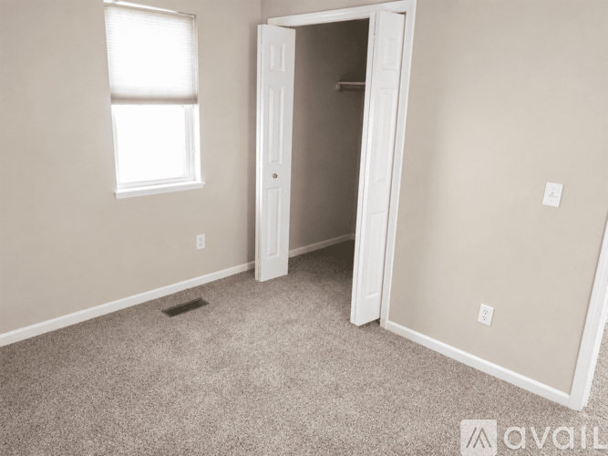 A room with a carpeted floor, a window, and a door.
