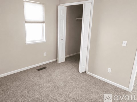 A room with a carpeted floor, a window, and a door.
